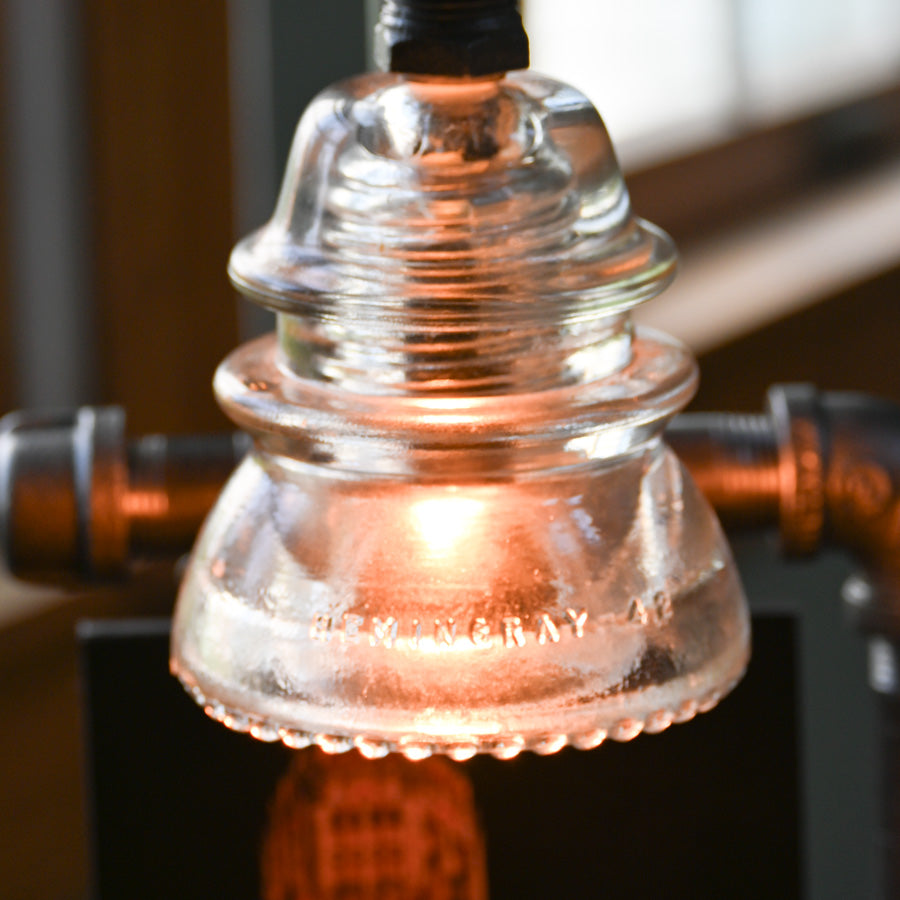 Close-up of clear glass insulator on steampunk lamp with warm LED glow. Unique lighting accent inspired by Buffalo NY landmarks.