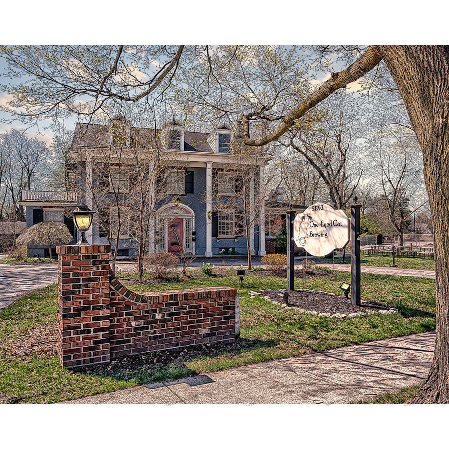 Nanobrewery photo in Williamsville featuring One-Eyed Cat Brewery's Colonial Revival building with spring trees and a brick signpost.