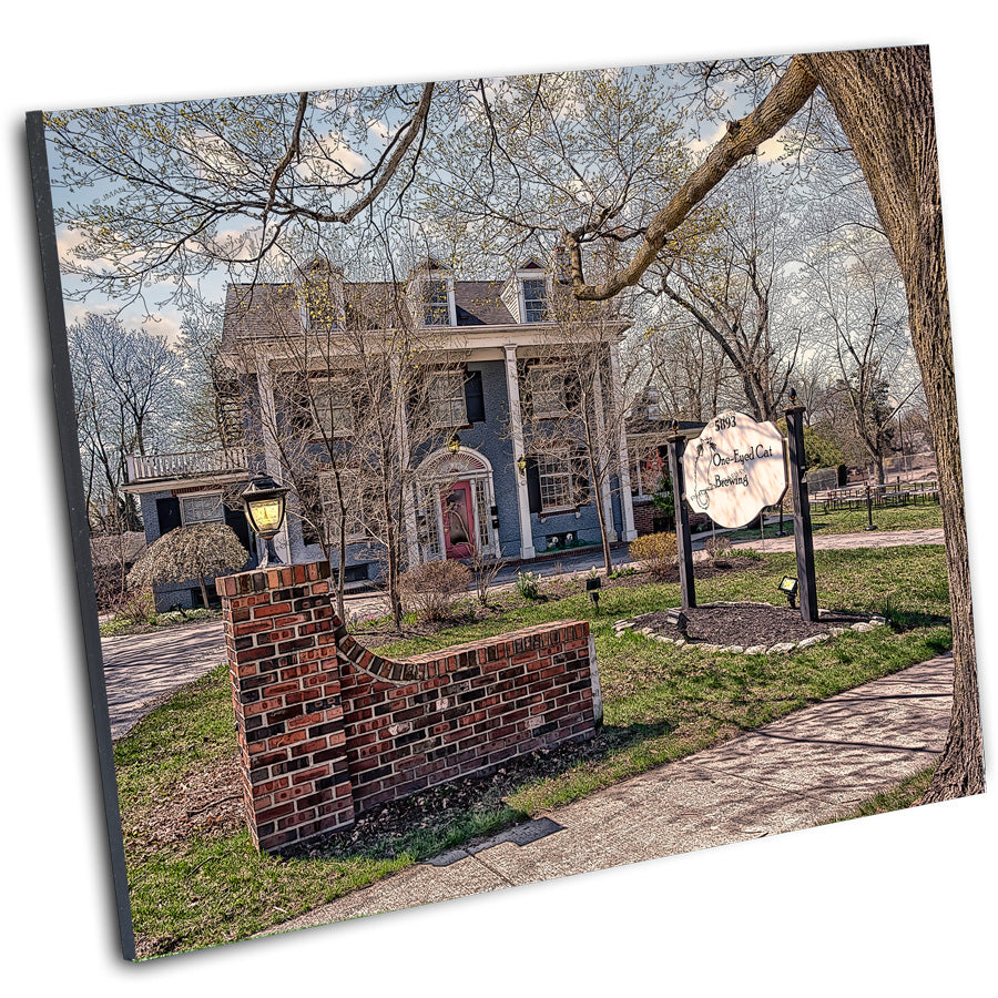 Mounted print of One-Eyed Cat Brewery in Williamsville, NY, showcasing its historic architecture and landscaped surroundings.