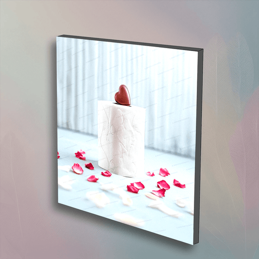 Valentine's Day toilet paper wall art featuring a roll with a heart-shaped chocolate on top, surrounded by rose petals. Unique festive bathroom decor.