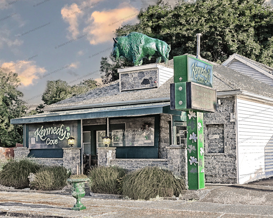 Kennedy's Cove restaurant exterior in Clarence, NY, featuring a green buffalo statue and signage promoting hand-cut steaks and blackened seasoning.