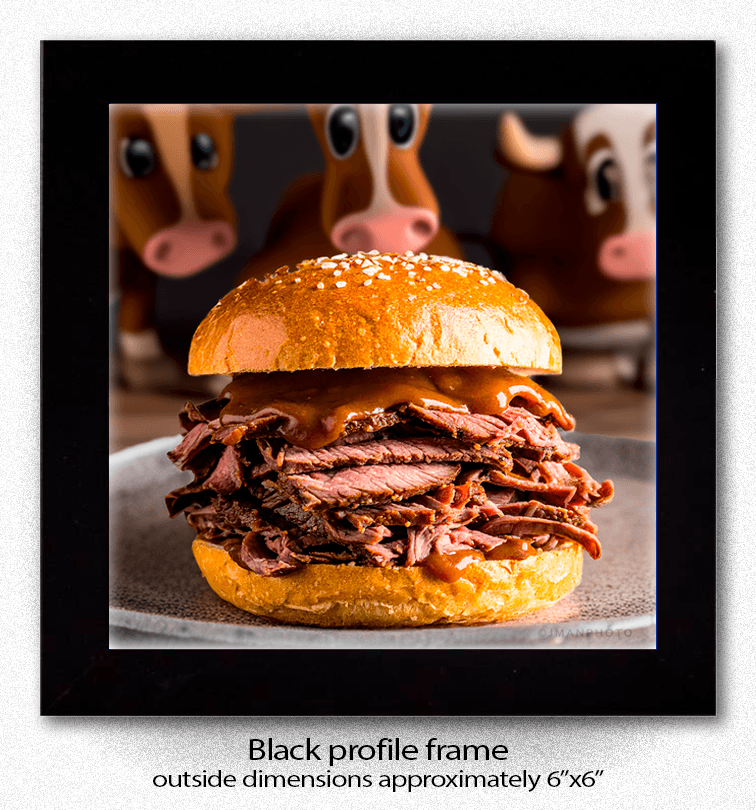 Framed Beef on Weck Funny Comical Coaster displayed in a black profile frame, showcasing a comical roast beef sandwich image with cartoon cows, ideal for kitchen decor.