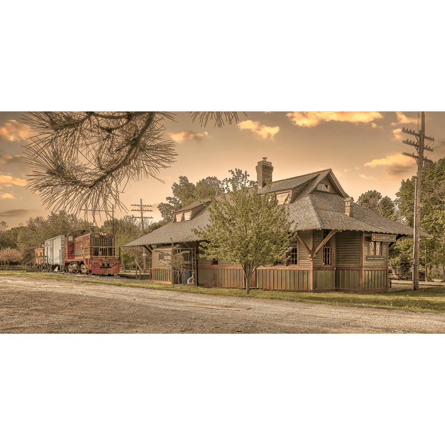Williamsville Train Station Art - Depot-Locomotive print featuring a historic train depot and vintage locomotive under a warm sky, ideal for nostalgic decor.