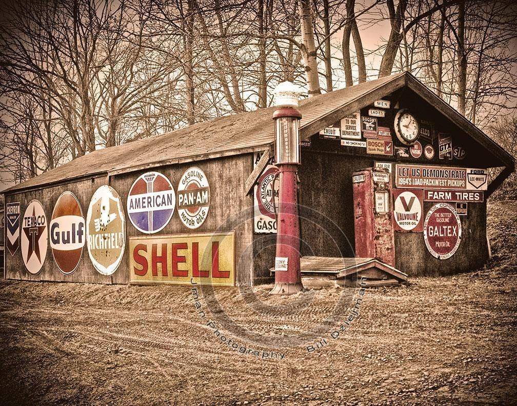 Vintage gas station signs wall art print featuring Shell, Gulf, Texaco, and a gravity fuel pump on a rustic shed. Ideal decor for automotive enthusiasts.