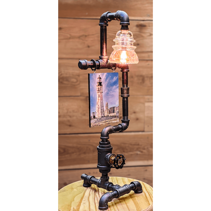 Steampunk Lamp with Insulator features a clear glass insulator light, 5x7 lighthouse photo, and valve switch on black iron pipe base. Ideal for vintage decor.