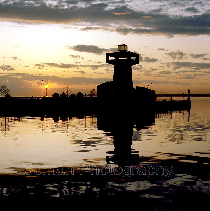 Silhouette of Erie Basin Marina Tower lighthouse at sunset with reflection on water