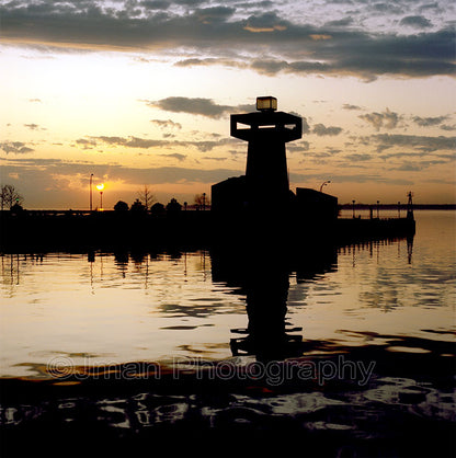 Silhouette of Erie Basin Marina Tower lighthouse at sunset with reflection on water