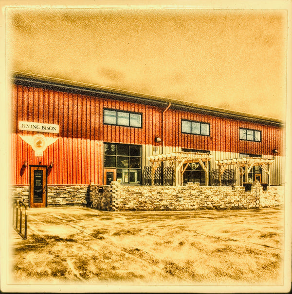 A  photograph of a red metal building with large windows, a stone foundation, and a sign reading 'FLYING BISON.' This appears to be a real outdoor architectural scene rather than a clean product shot, chart, swatch, or instruction graphic.