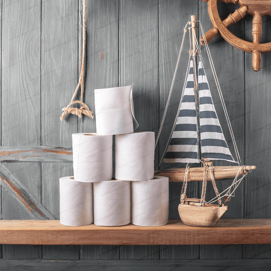 Sailboat Theme Roll of Toilet Paper Bathroom Wall Art featuring stacked toilet paper rolls beside a decorative sailboat and ship wheel on wooden shelf.